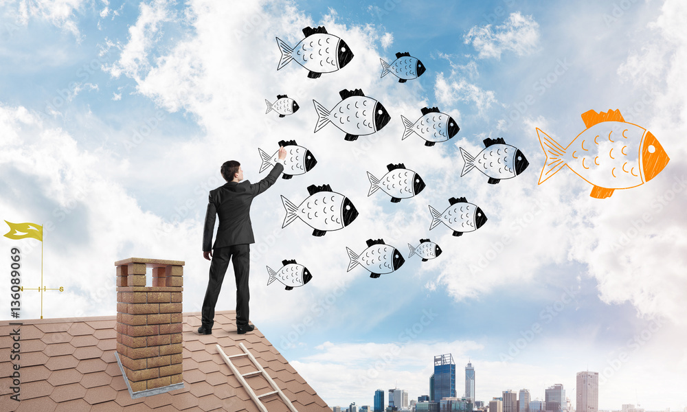 Businessman standing with back on house brick roof and drawing. Mixed media Businessman standing with back on house brick roof and drawing. Mixed media
