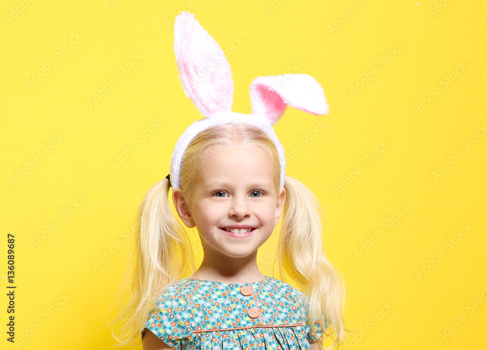 Cute little girl with bunny ears and chocolate rabbit on color background