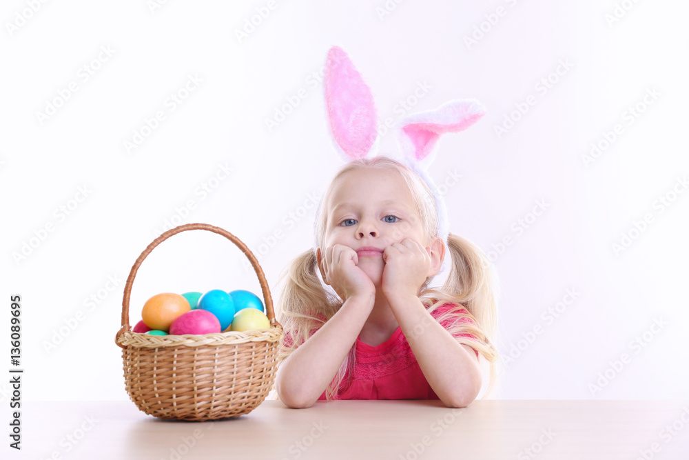 Cute little girl with bunny ears and basket full of Easter eggs on white background Cute little girl with bunny ears and basket full of Easter eggs on white background