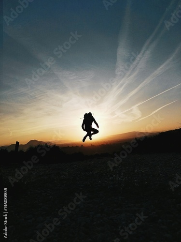 Boy jumping in front of sunset.