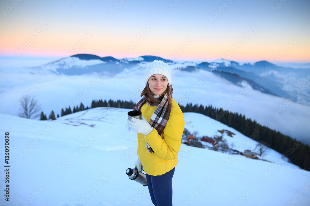 Young woman hiking in winter mountains. Woman drinking warm tea in the mountai.