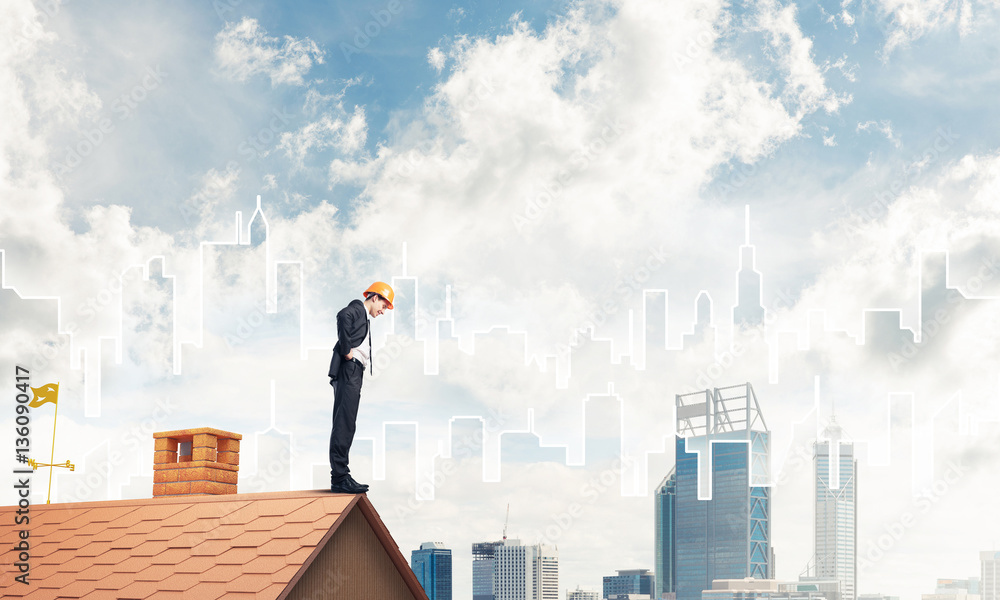 Engineer man standing on roof and looking down. Mixed media Engineer man standing on roof and looking down. Mixed media
