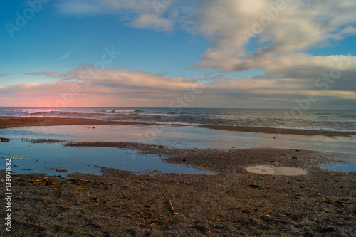 Sunset on beach. sea landscape  wirh red sky and clouds. Beach with waves and rocks  