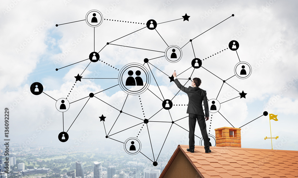 Businessman on house roof presenting networking and connection concept. Mixed media Businessman on house roof presenting networking and connection concept. Mixed media