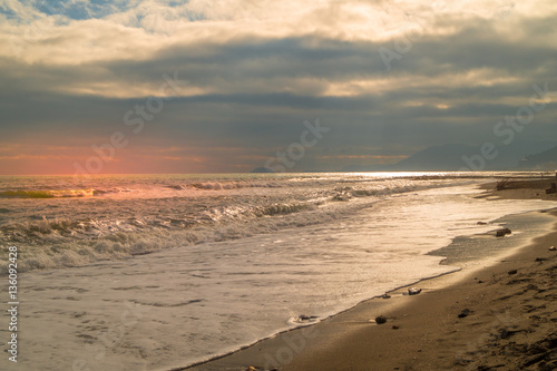 Sunset on beach. sea landscape  wirh red sky and clouds. Beach with waves and rocks  