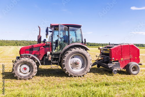 Red tractor in the field on a hay