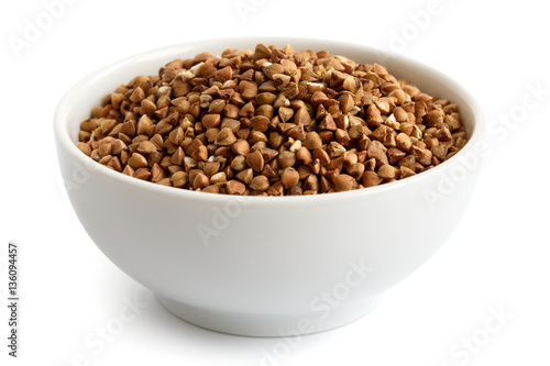 Dry buckwheat in white ceramic bowl isolated on white.