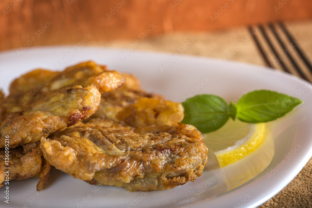 Pork brain panne on plate with lemon Pork brain panne on plate with lemon