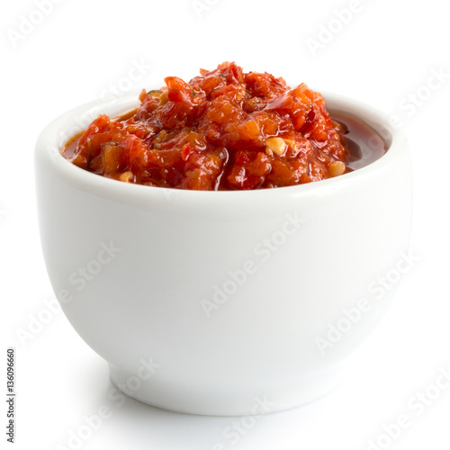 Red chopped chilli peppers in oil in ceramic white bowl.