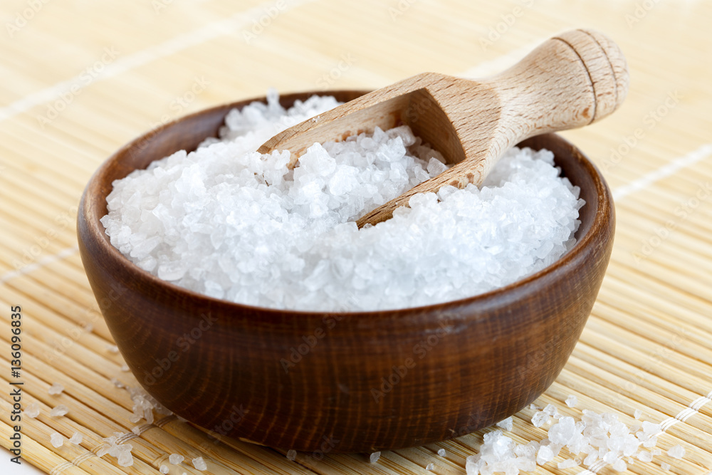 Rock salt in wooden bowl with wooden spoon on bamboo matt. Rock salt in wooden bowl with wooden spoon on bamboo matt.