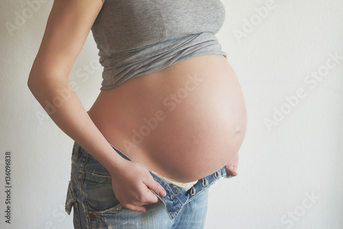 Pregnant woman trying to wear her jeans photo