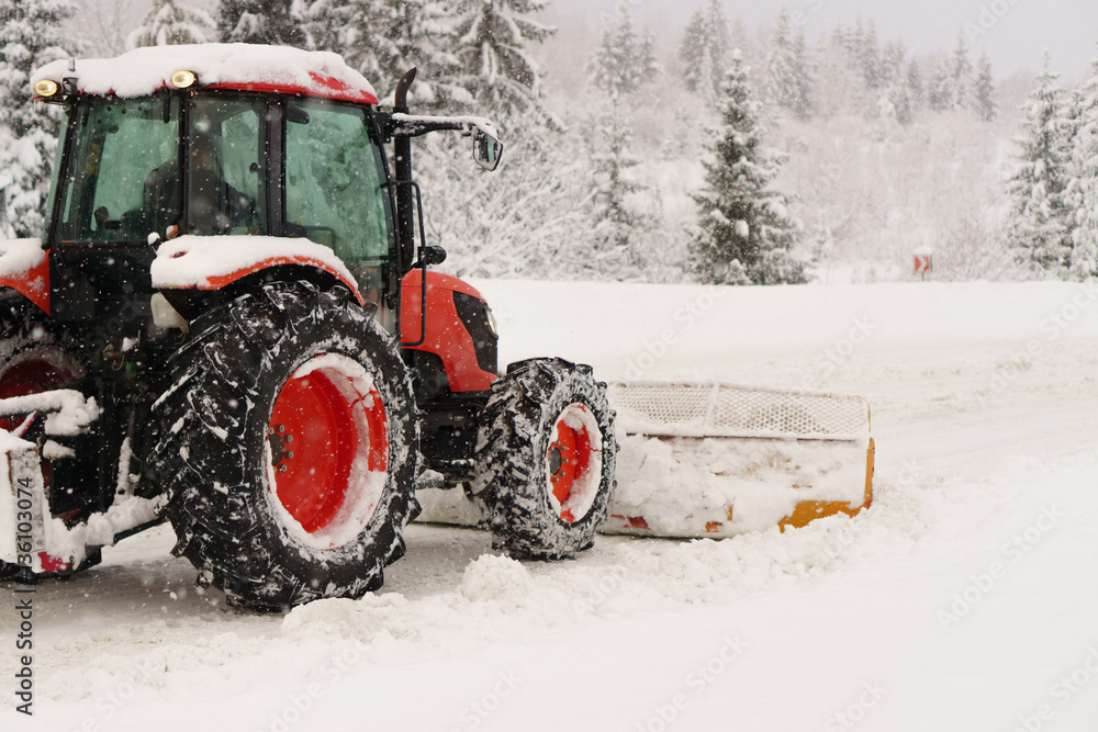 Red snowblower grader clears snow covered ski resort road in mountains or city street. Winter snowflake snowfall weather. Horizontal, copy space. Red snowblower grader clears snow covered ski resort road in mountains or city street. Winter snowflake snowfall weather. Horizontal, copy space.
