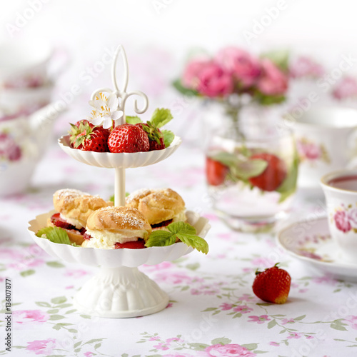 Profiterole or cream puffs cakes filled with whipped cream, strawberries in plateau