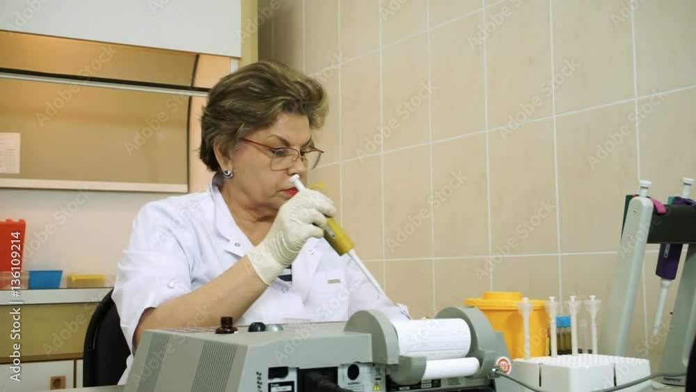 Biochemistry laboratory. Female laboratory assistant analyzing samples of blood at modern equipment. HD Biochemistry laboratory. Female laboratory assistant analyzing samples of blood at modern equipment. HD