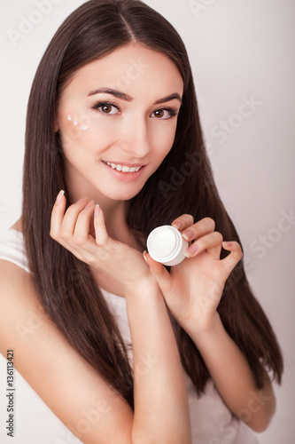 Skin Care. Beautiful healthy young woman with long hair, caring for their skin. Use cream for body care. Beauty and health