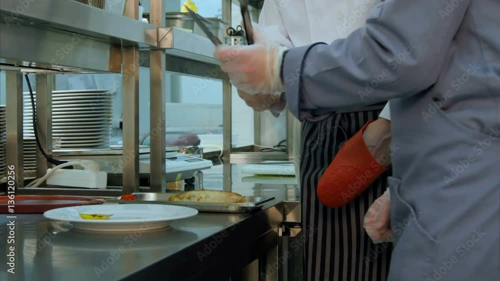 Chef teaching cook trainee how to serve the cooked dish properly Chef teaching cook trainee how to serve the cooked dish properly