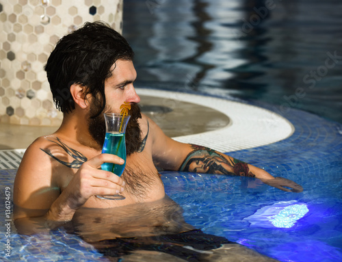 Man drinks cocktail in pool