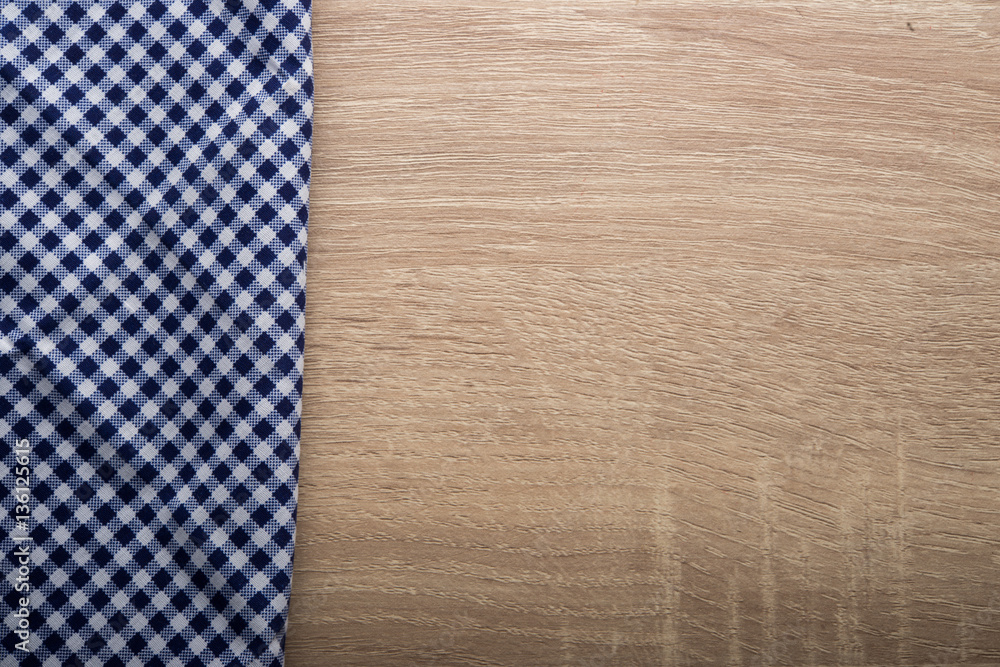 Checkered blue napkin on wooden background.
