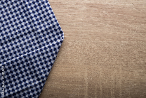 Checkered blue napkin on wooden background.