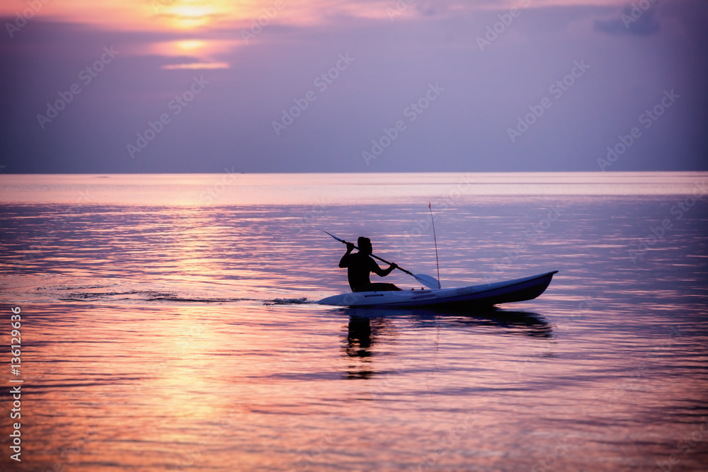 Silhouette of a man on a sea kayak on a colorful sunset