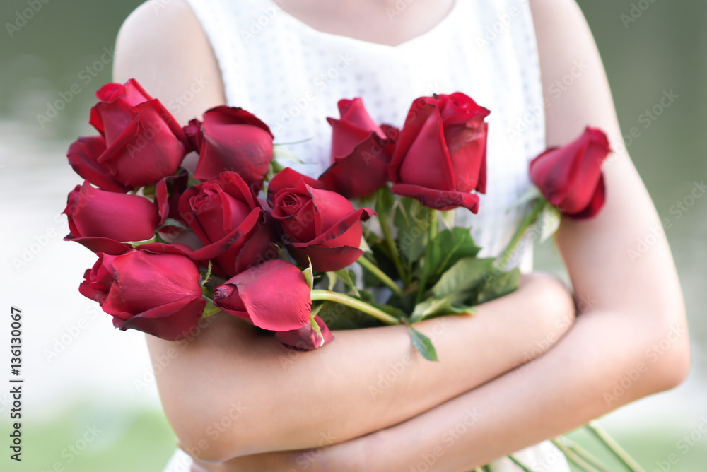 Woman hugging red roses with pleasure.