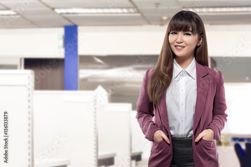 Attractive asian business woman standing in front of desk