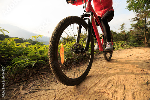 young woman riding mountain bike on forest trail