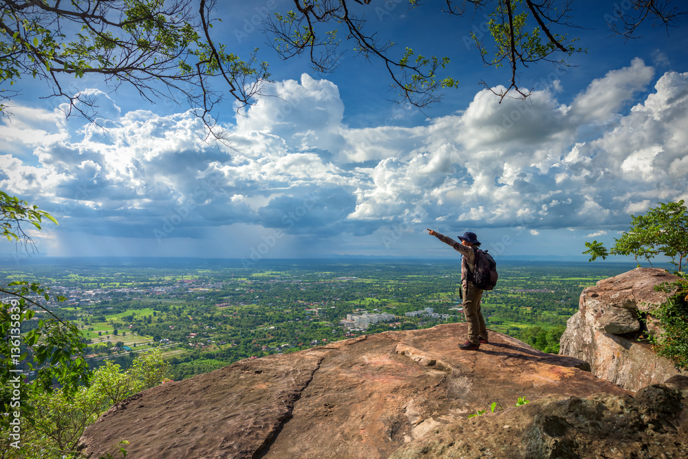 Young man traveler on cliff with beautiful landscape - success concept