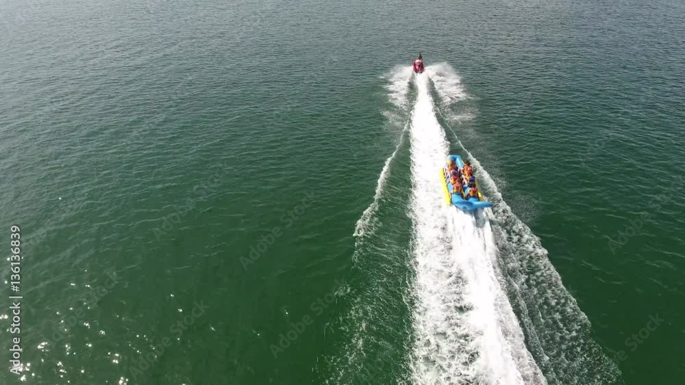 Water sport person boarding being pulled by scooter aerial view 4K. Flying behind a young wake boarding professional on sea being pulled by fast scooter. Water sport person boarding being pulled by scooter aerial view 4K. Flying behind a young wake boarding professional on sea being pulled by fast scooter.