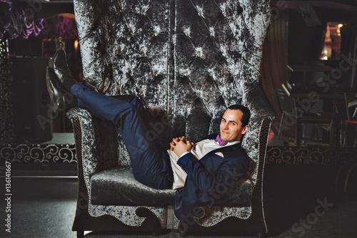 The man on the chair. In a blue suit, purple tie.