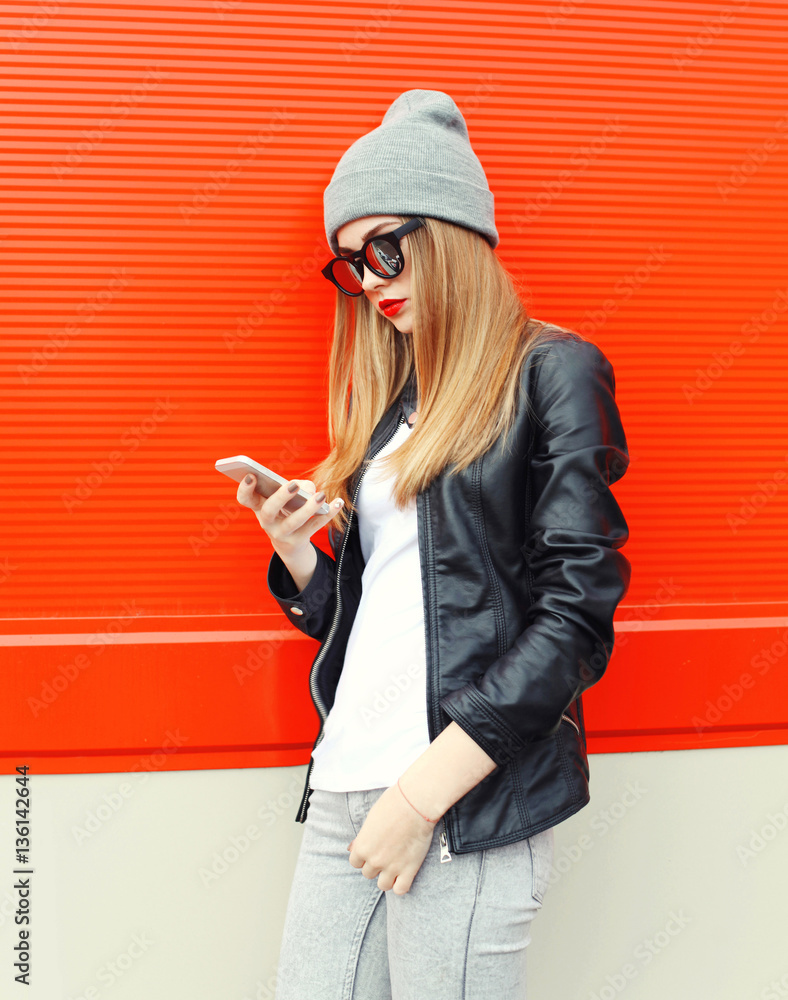 Fototapeta premium Fashion stylish young woman using smartphone walking in city ove