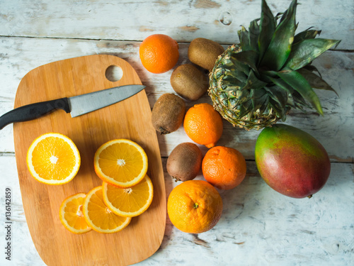 Top view of fruits on the table. Oranges, kiwi, mango, pinnaple. Healthy food and diet concept on vintage boards photo