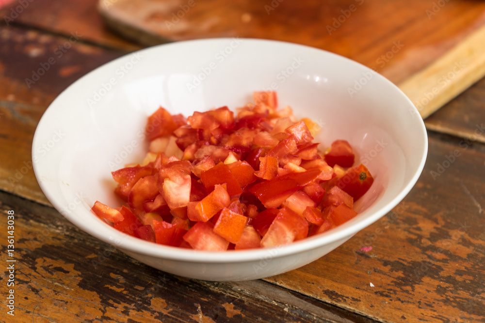Mujer cortando tomate para una receta en casa. Mujer cortando tomate para una receta en casa.