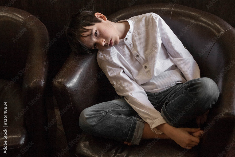 Boy in white shirt sitting in a chair. young boy imposingly placed in a leather couch. boy in shirt and jeans. Teenager relaxing in a cafe
Boy in white shirt sitting in a chair. young boy imposingly placed in a leather couch. boy in shirt and jeans. Teenager relaxing in a cafe