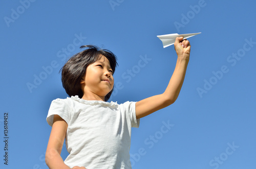 青空に紙飛行機を飛ばす女の子