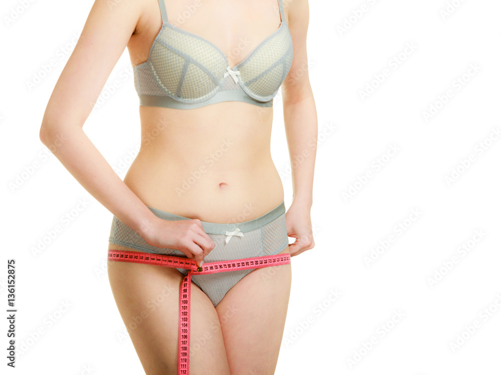 Woman in lingerie measuring her hips with measure tape.