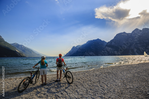 Mountain biking woman and young girl over Lake Garda.