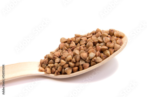 Uncooked buckwheat on wooden spoon. premium buckwheat groats on white background © allaordatiy