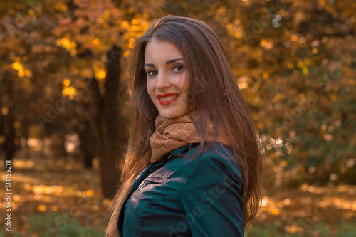 beautiful girl with red lipstick on lips stands in the Park by turning her head to the camera and smiling
