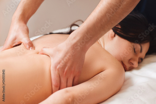 Chiropractor treating woman with pain in back. Young woman enjoying massage  free space. Body care  relax  health  alternative medicine  healthy spine  stress relief concept
