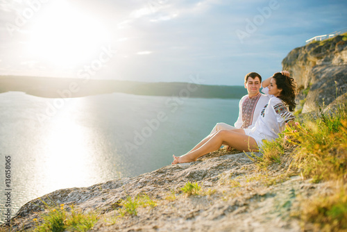 Couple wearing on dress with a pattern sitting at beautiful land