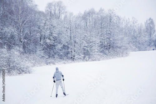 Skier  with skis on the snow track beside forest in the winter day. Country skiing. © fotoduets