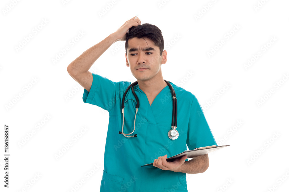 young man doctor posing in uniform with stethoscope and notepad isolated on white background in studio young man doctor posing in uniform with stethoscope and notepad isolated on white background in studio
