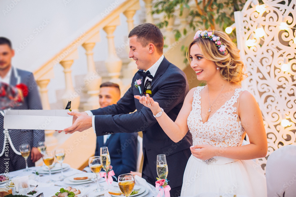 Newlyweds get an original gift butterfly from mother. Shocked and smiling bride. Groom emotions.