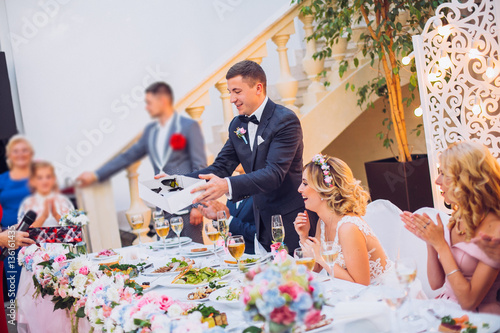 Newlyweds get an original gift butterfly from mother. Shocked and smiling bride. Groom emotions.