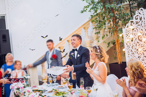 Obraz na płótnie Newlyweds get an original gift butterfly from mother. Shocked and smiling bride. Groom emotions. w salonie