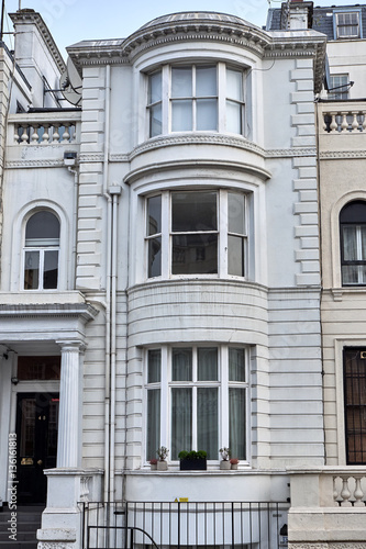 Narrow building with bay windows in an ornamented facade with ashlar walling, pillars and decorated parapets, in London city