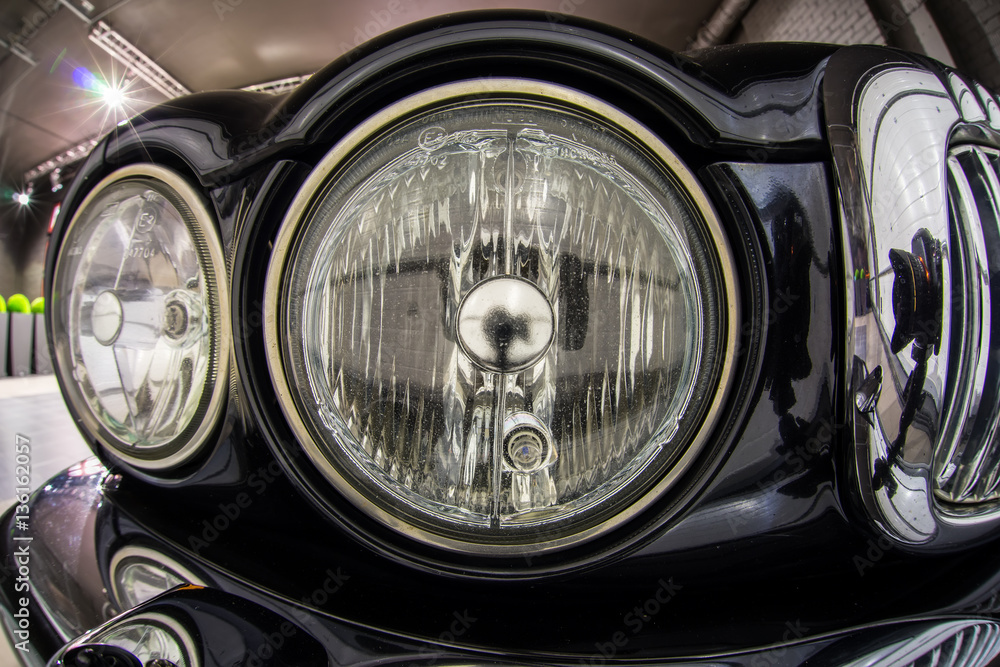 Close up high detailed view on headlights of black retro luxury car.