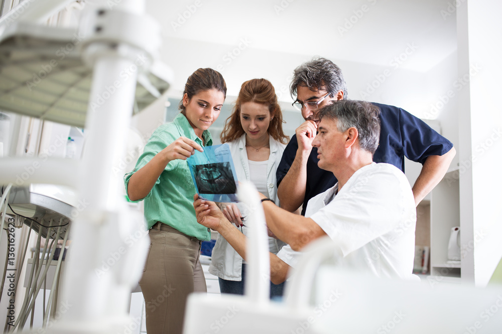 A group of dentists attentively examines X-ray images of a patient's teeth, ensuring precise diagnoses and comprehensive dental care. A group of dentists attentively examines X-ray images of a patient's teeth, ensuring precise diagnoses and comprehensive dental care.