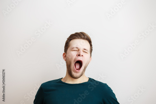 Yawing  young man on a light background